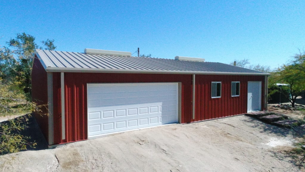 Red steel building with gutters and ridge vents windows and roll french door