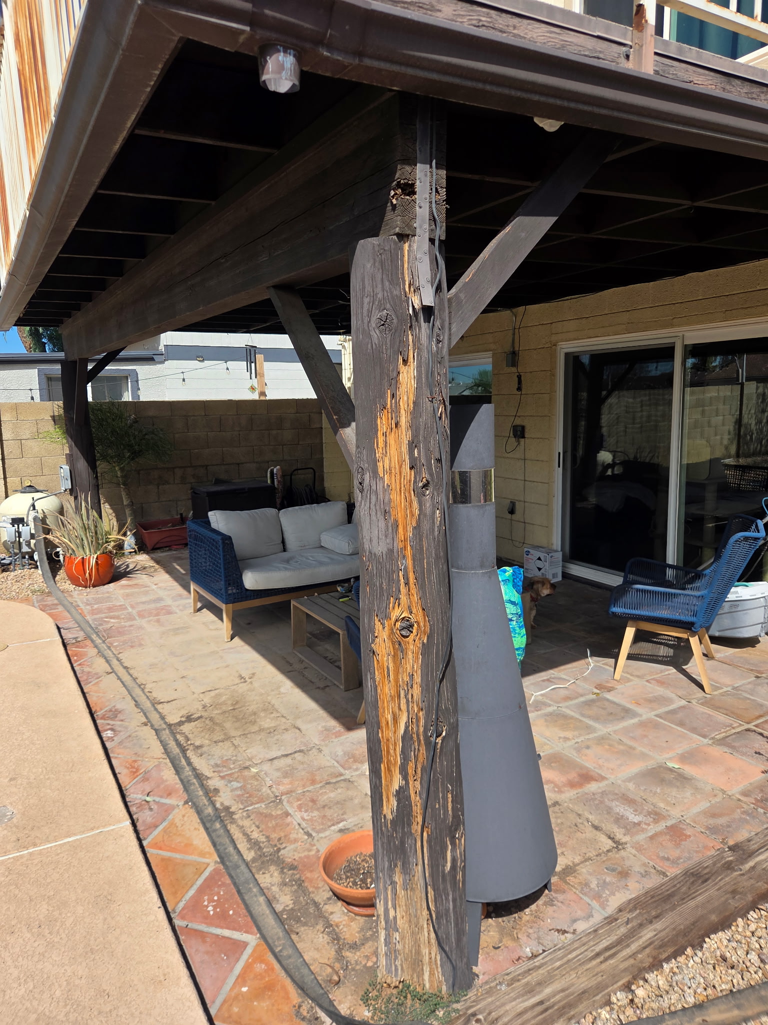 Before replacement: deteriorated wood support post beneath a patio deck